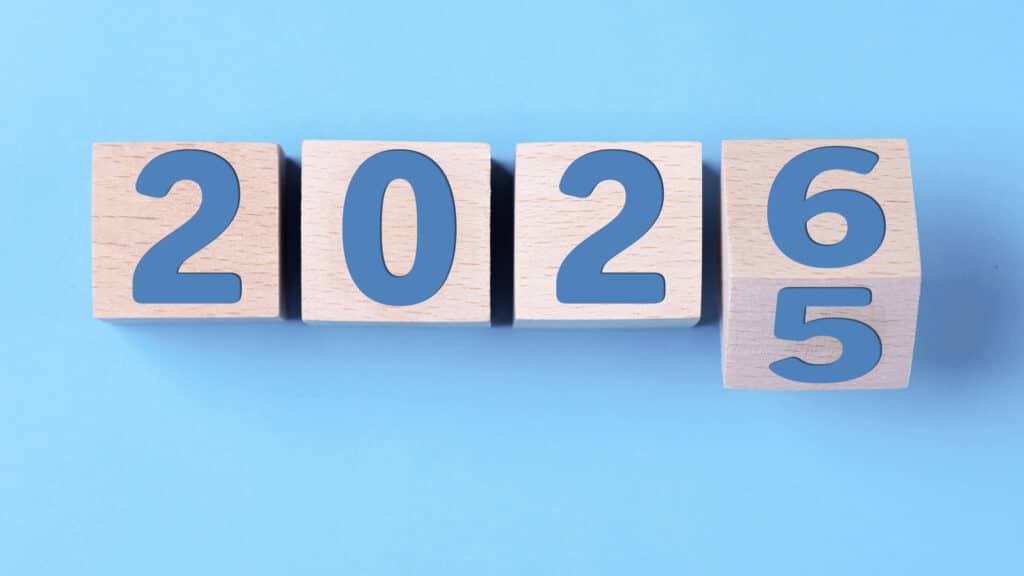 Holzwürfel mit den Zahlen 2026 und 5 auf einem blauen Hintergrund.