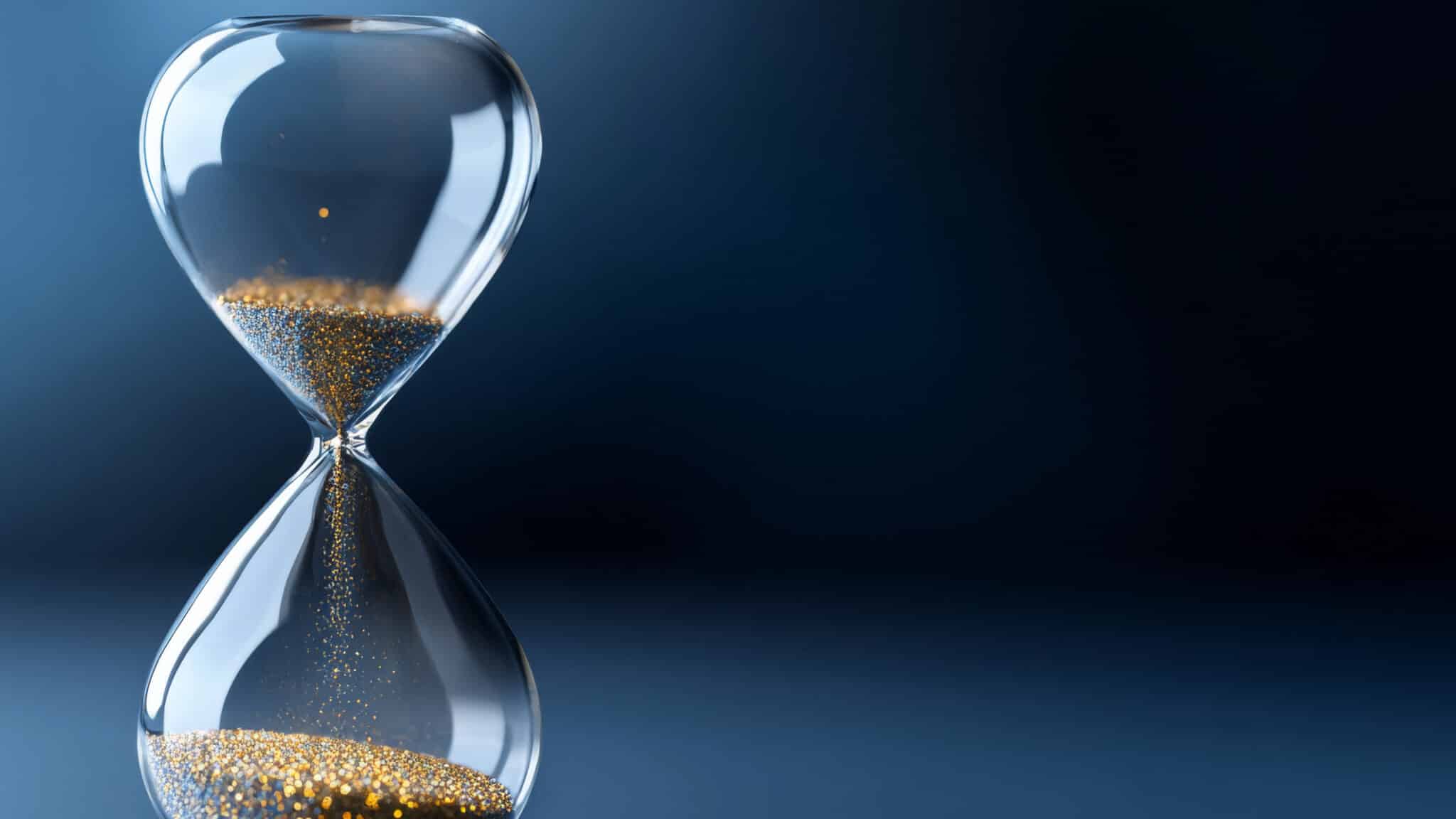 Eine gläserne Sanduhr mit goldenen Körnern symbolisiert die Schlussbilanz 2026 und den zeitnahen Ablauf von Fristen im Umwandlungsrecht.
